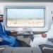Two passengers seated across a table inside an Etihad Rail passenger train