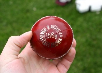 Red cricket ball in a hand; illustrative photograph, not from India Women vs Zimbabwe Women match