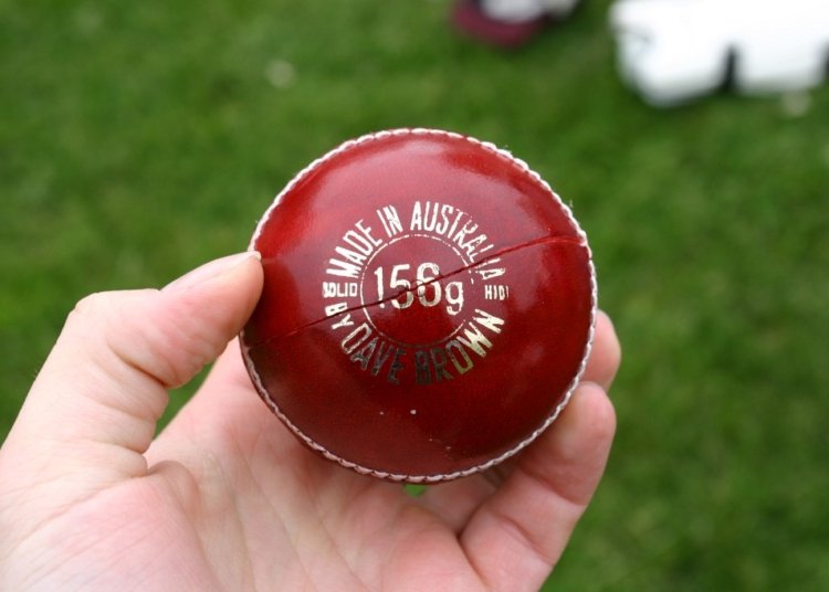 Red cricket ball in a hand; illustrative photograph, not from India Women vs Zimbabwe Women match