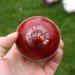Red cricket ball in a hand; illustrative photograph, not from India Women vs Zimbabwe Women match