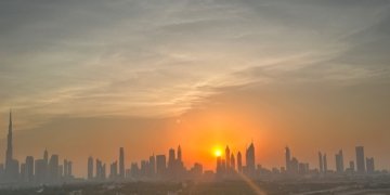 Dubai skyline and Burj Khalifa silhouetted against the setting sun